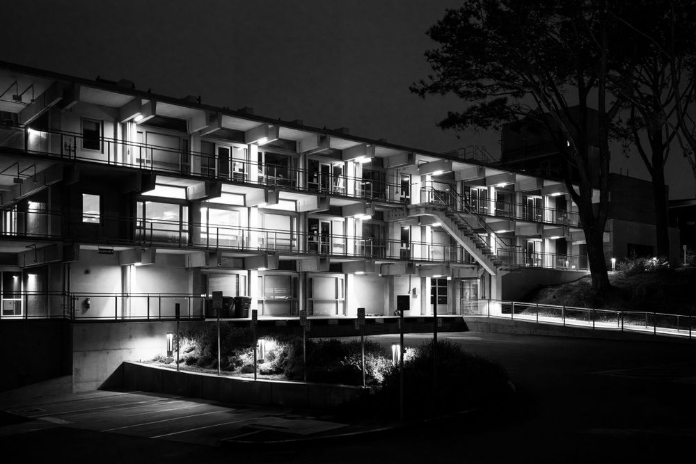 Modern tiered motel building lit up at night in black and white photography in La Jolla, California.