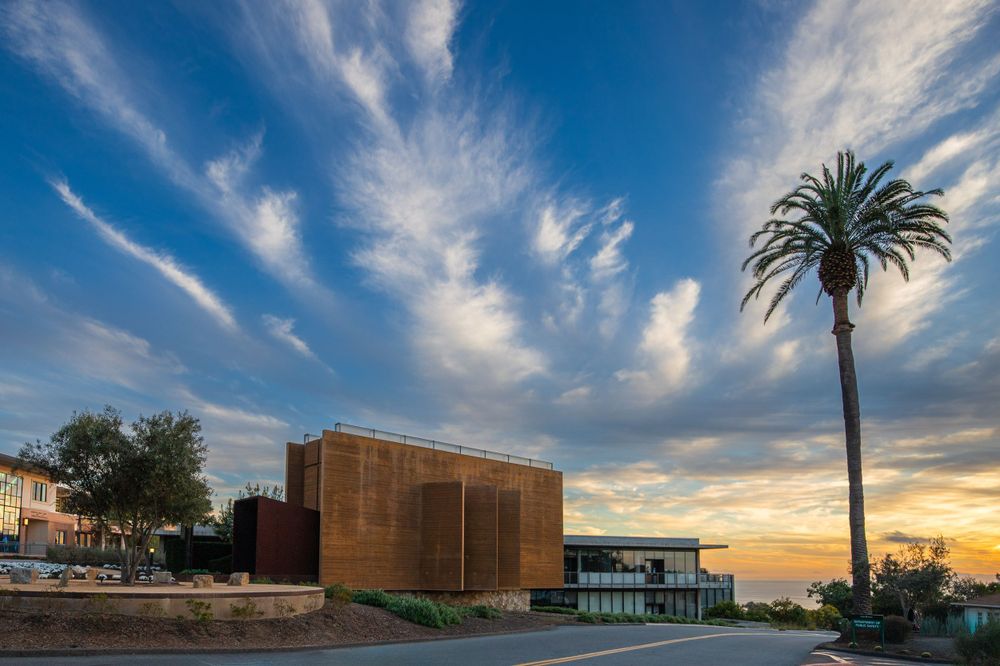 Modern concrete building exterior with red lighting at dusk against cloudy sky the PLNU campus.