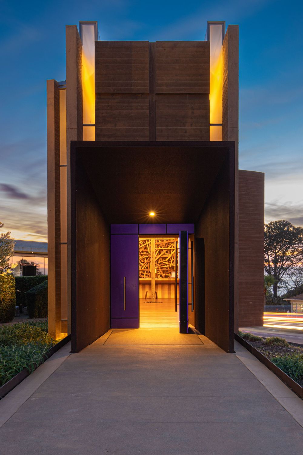 Modern architectural entrance with purple door and warm lighting at twilight on the PLNU campus.