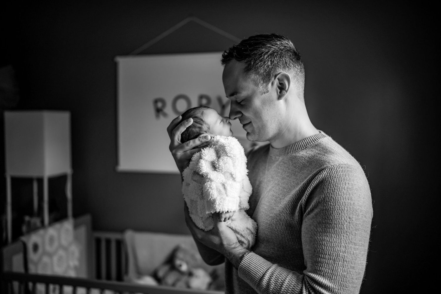 Black and white photo of someone holding and gazing lovingly at a small dog.