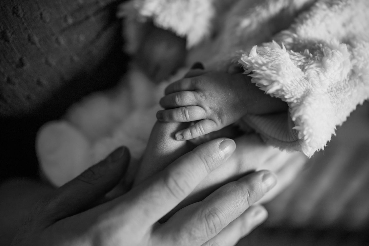 Close-up black and white photo of hands gently touching against a soft background.