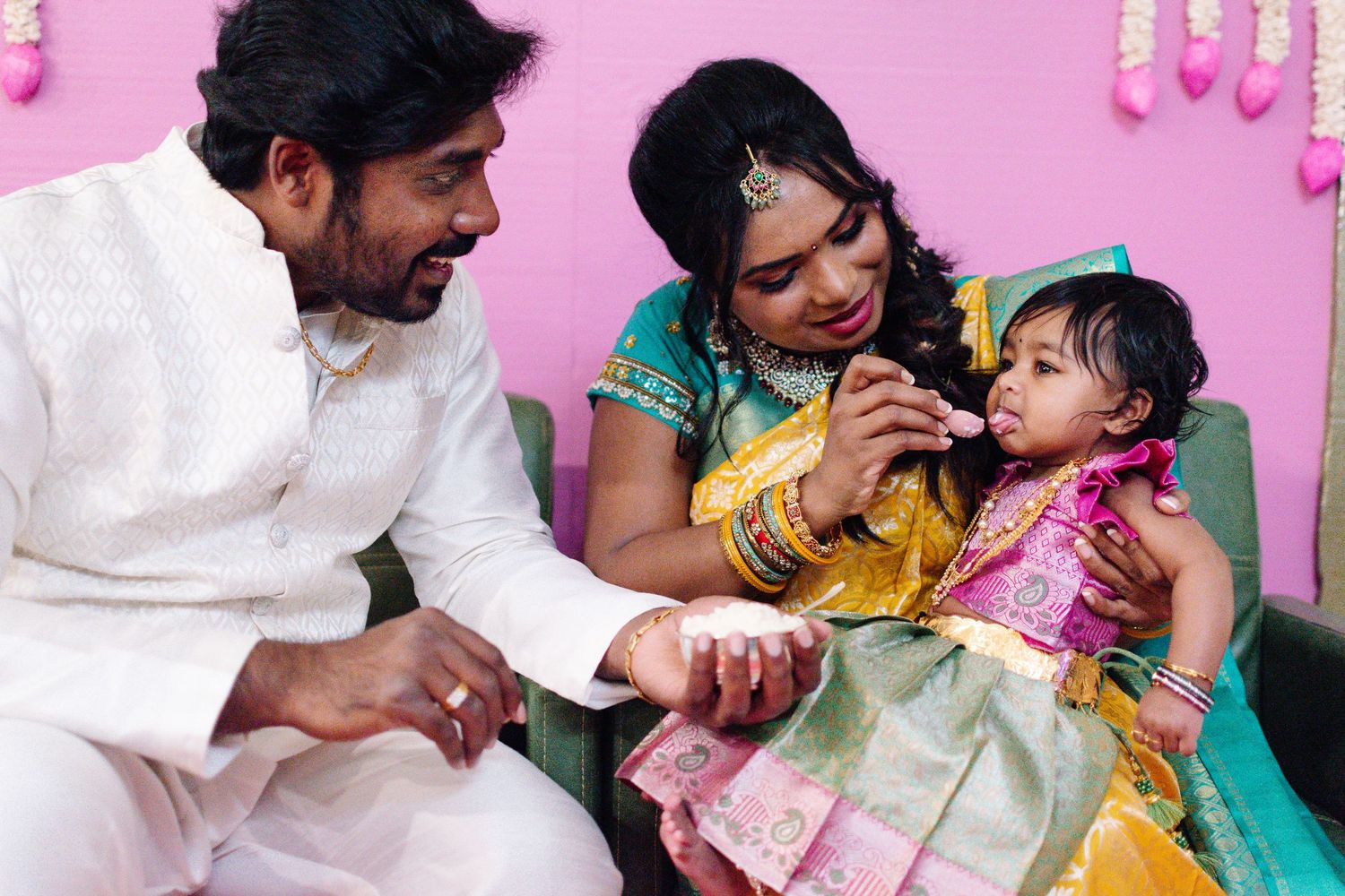 Parents helping baby take their first bite during the Annaprashana ceremony in Seattle.