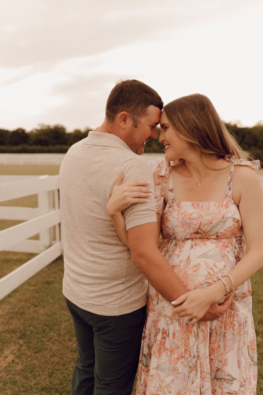 Elegant maternity portrait of a woman with a glowing smile, standing in a scenic outdoor location.