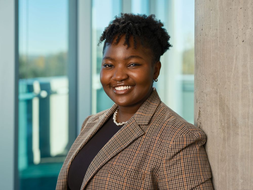 Portrait of a smiling woman in a checked blazer with natural daylight background — photographed by Khoi Ly in Vancouver.