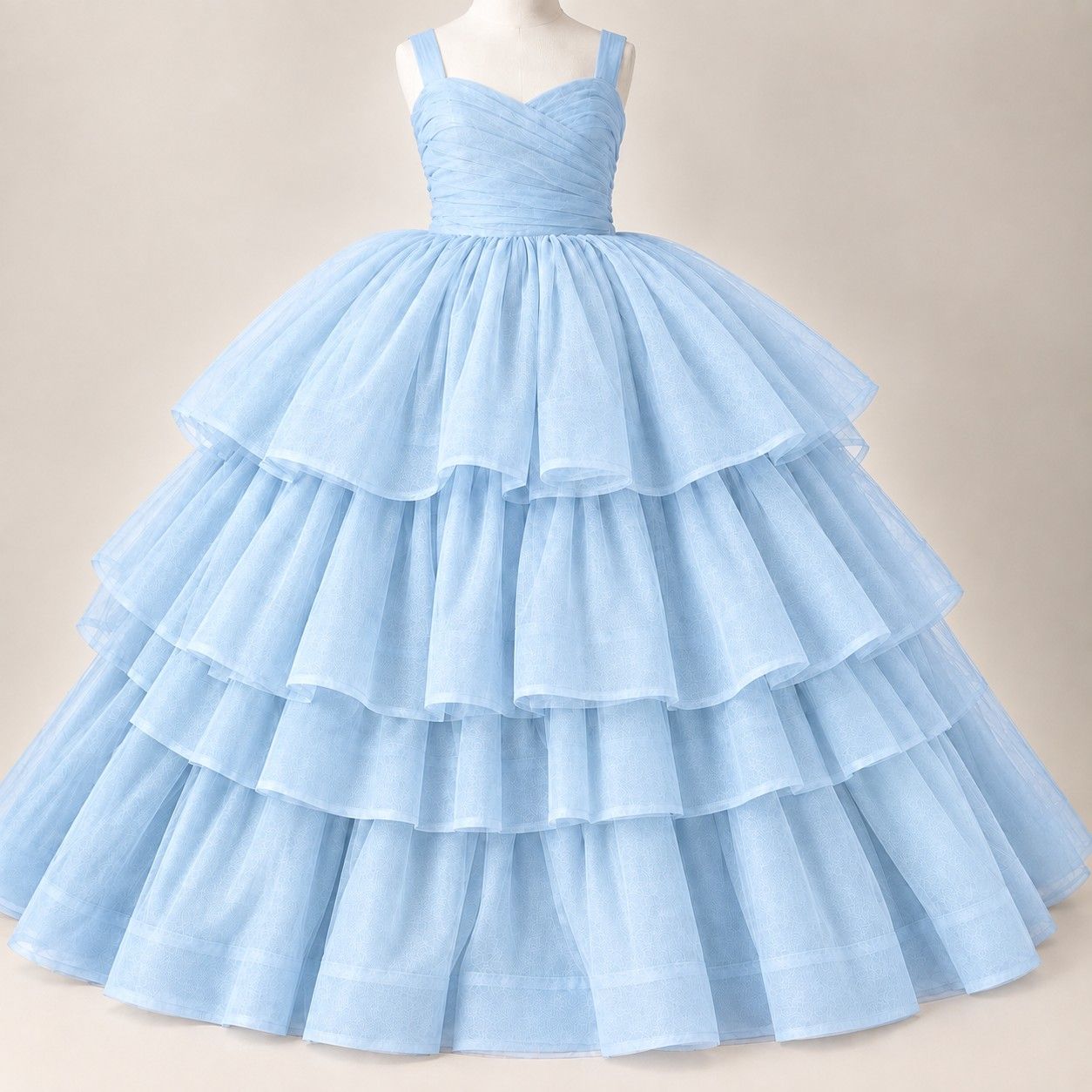 An elegant portrait featuring a flowing light blue tulle gown against a soft blue studio backdrop.