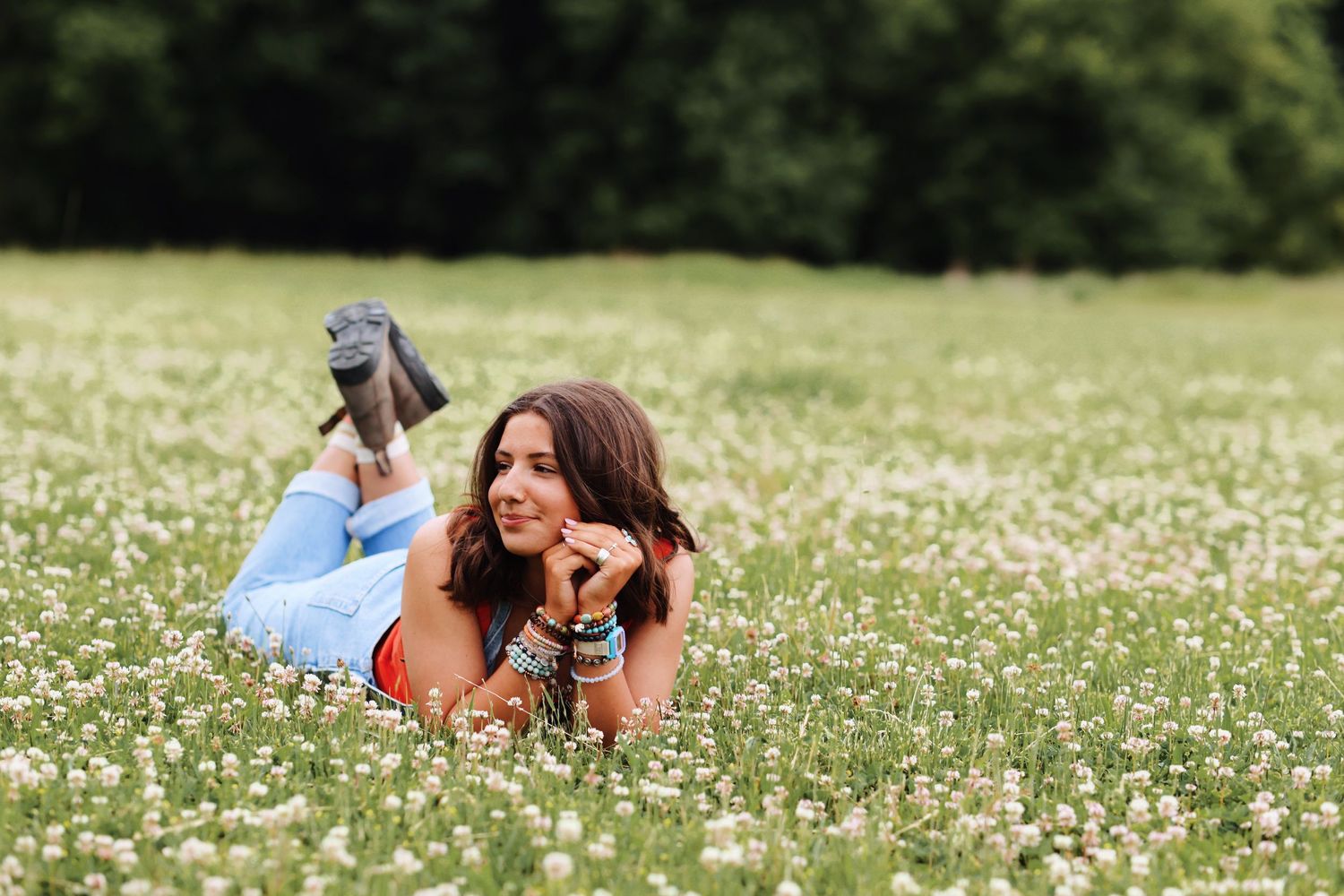 Woman lying in field of white wildflowers on sunny day.