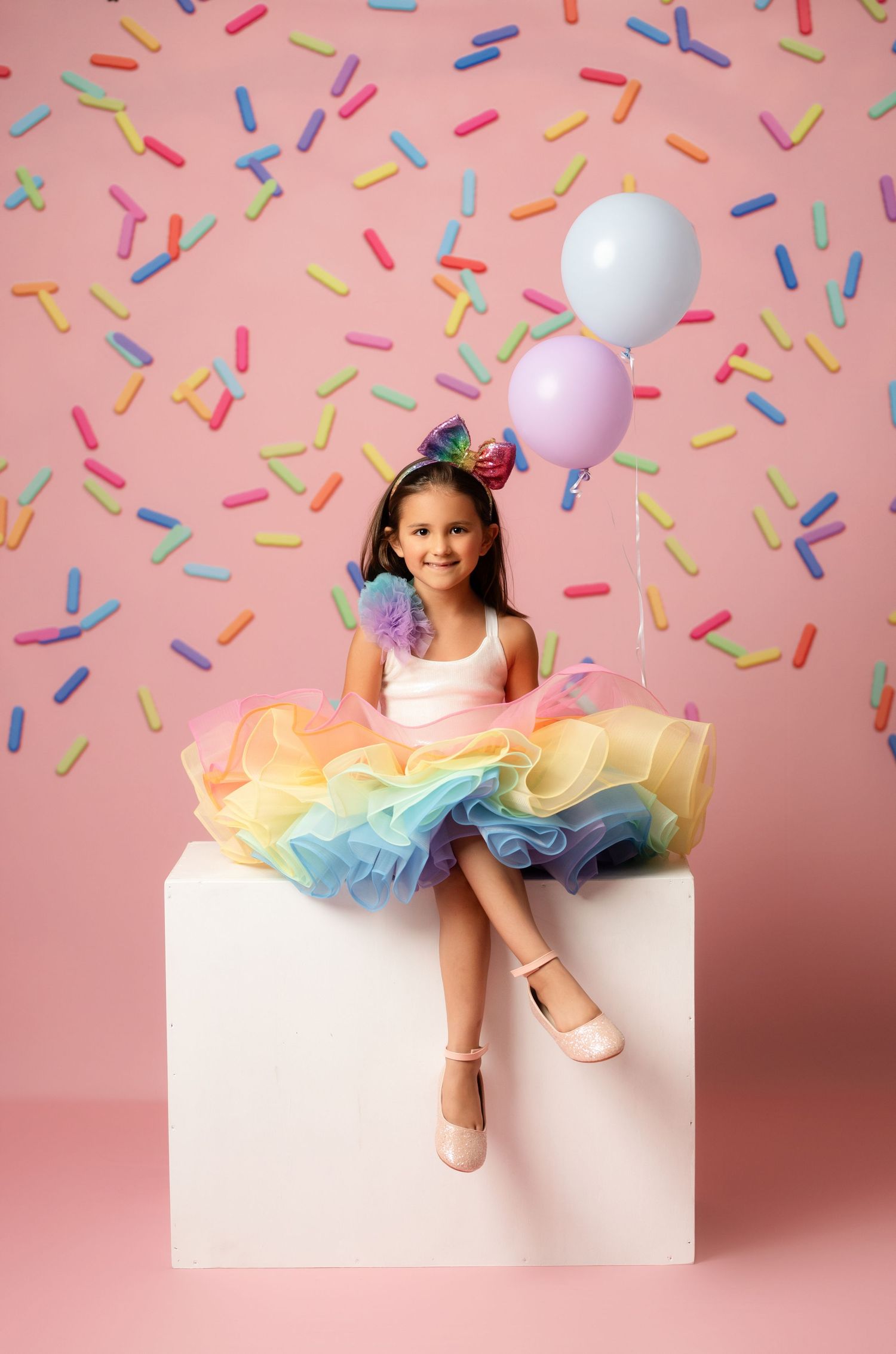 Playful multi-colored tulle dress in pastel mint and purple against pink backdrop.