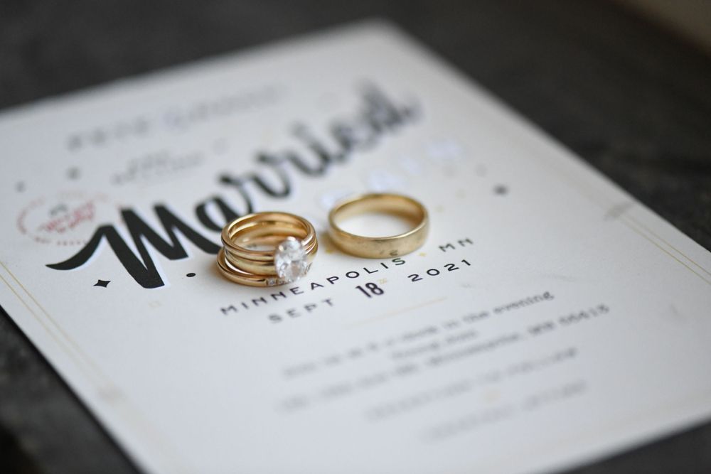 Wedding rings resting on elegant white invitations with calligraphy text.