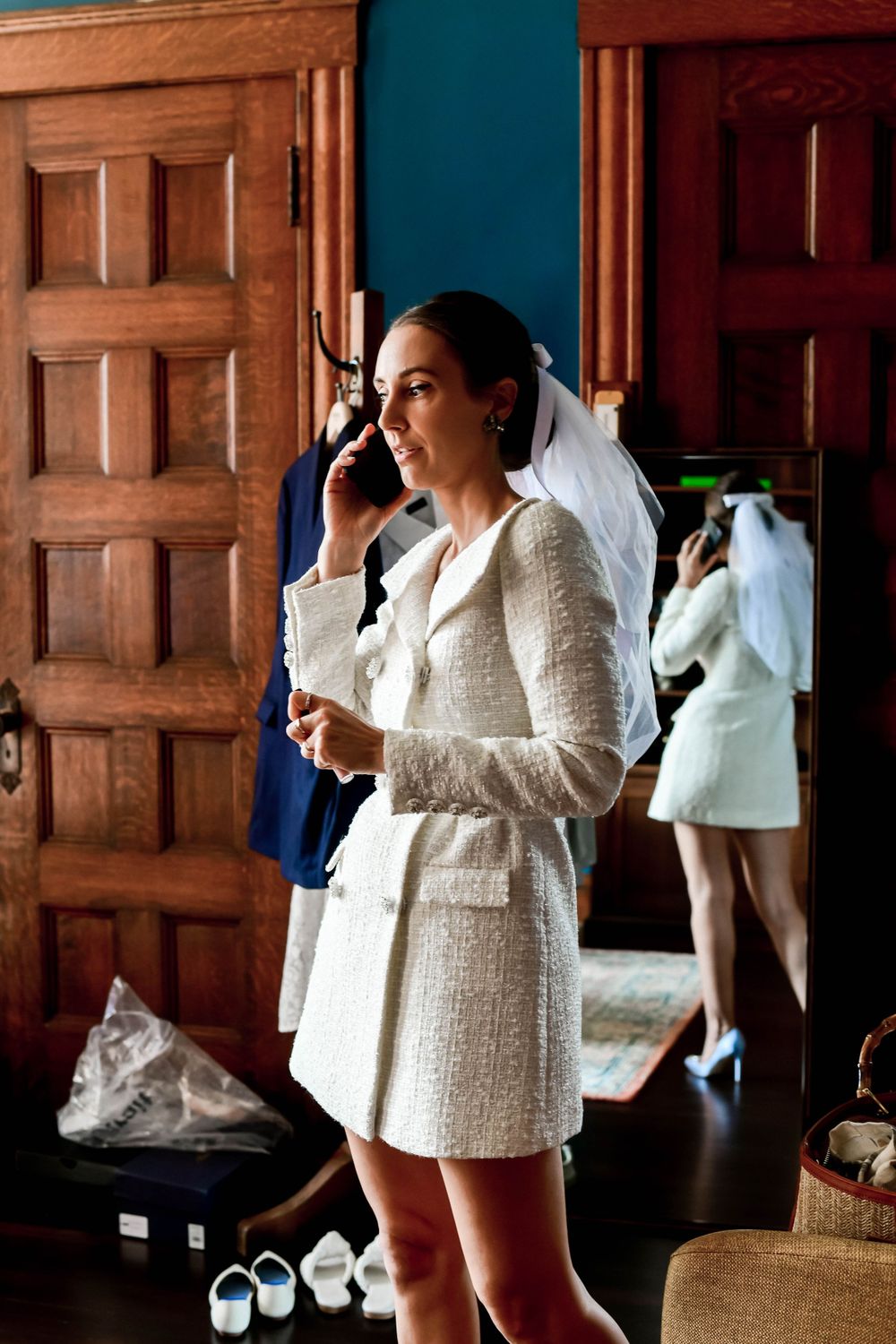 Person in white jacket getting ready in wood-paneled room with mirrors and doors.