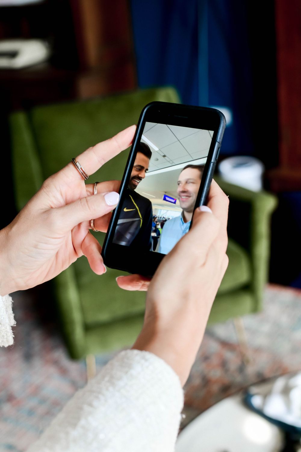 Hands holding a smartphone displaying a video chat conversation in a casual indoor setting.
