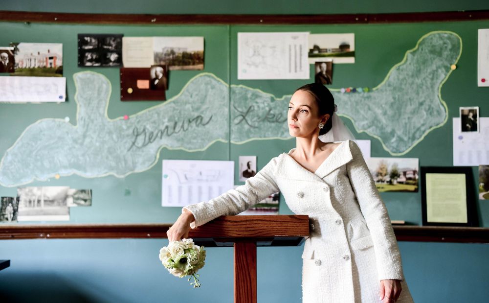 Woman in white coat posing next to a decorative wall with maps and historical photos.