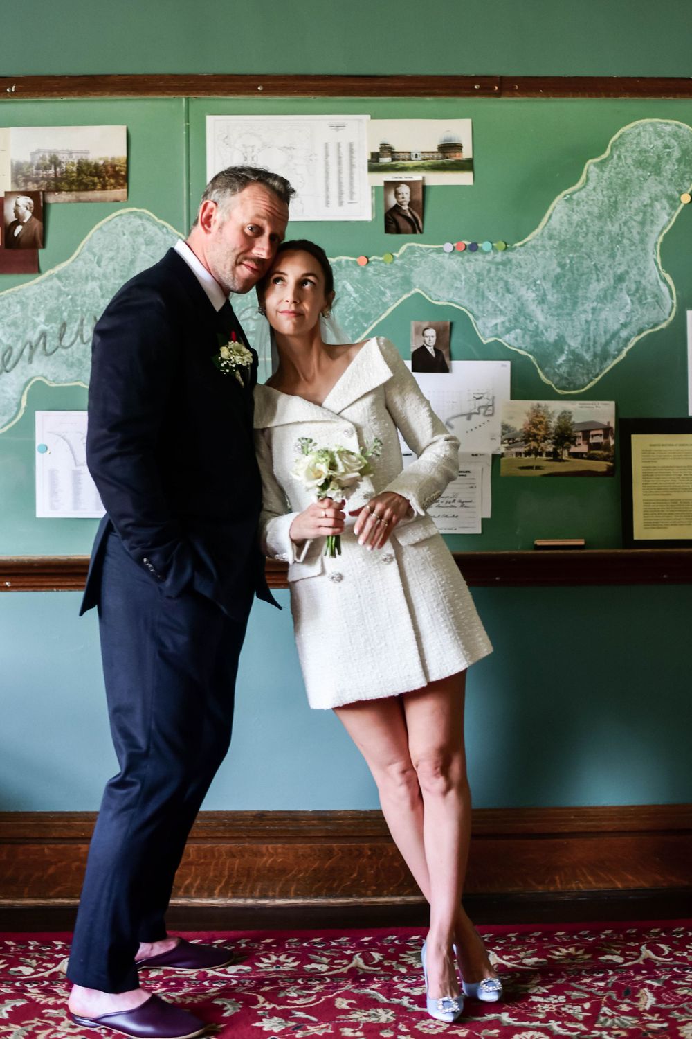 Wedding couple posing together against wall with vintage maps and photographs.