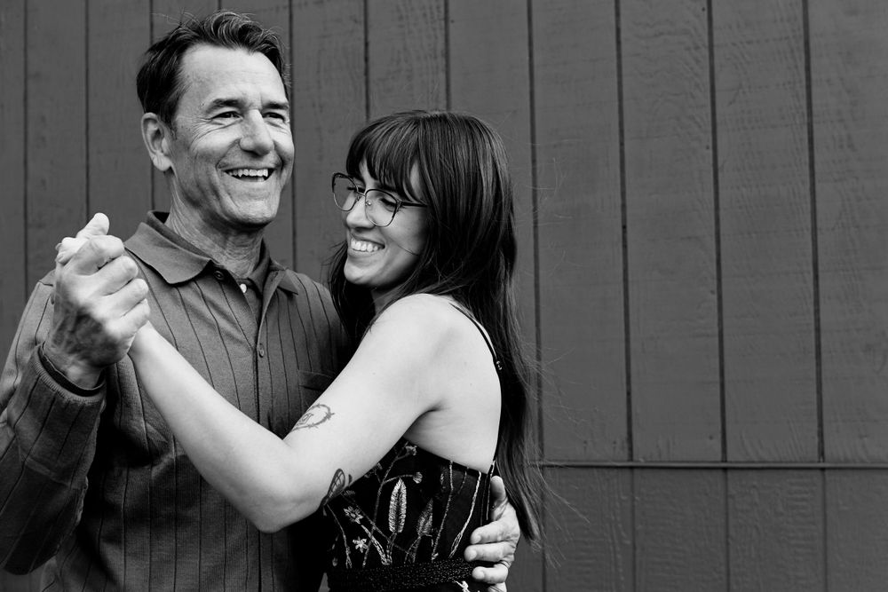 Candid black and white photos of couple sharing joyful moments against wooden wall.