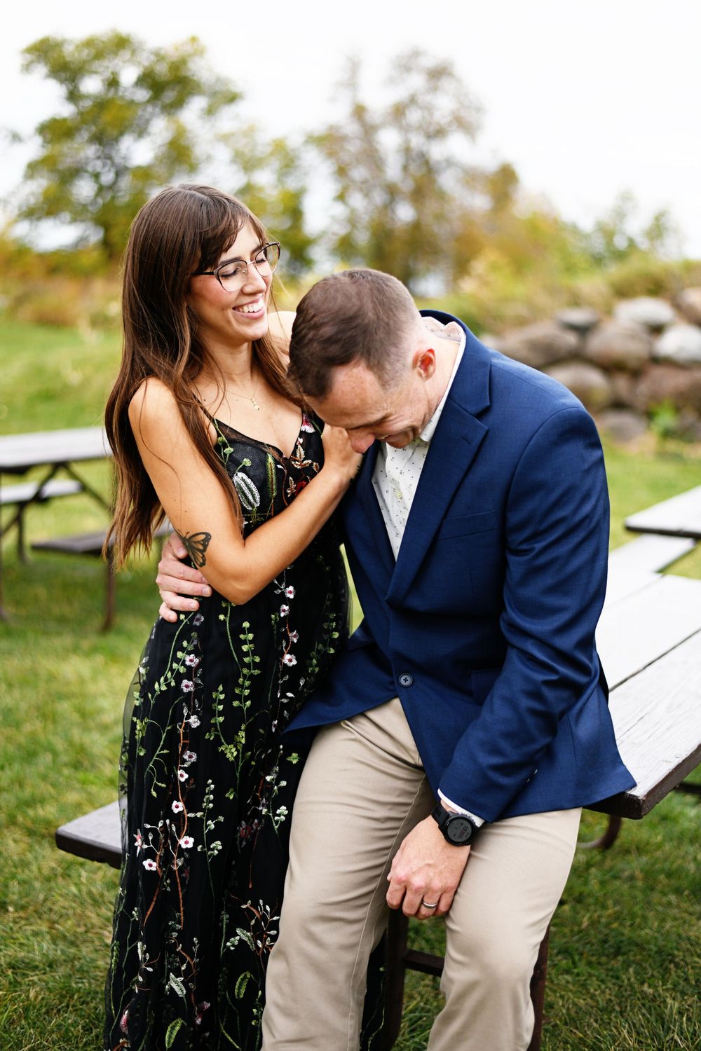 Couple laughing and embracing during outdoor photo session in park setting.