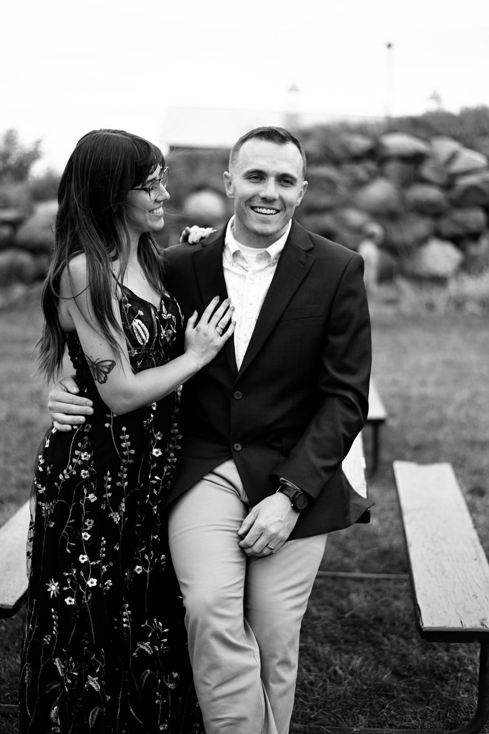 Romantic black and white engagement photos taken outdoors on a picnic bench.