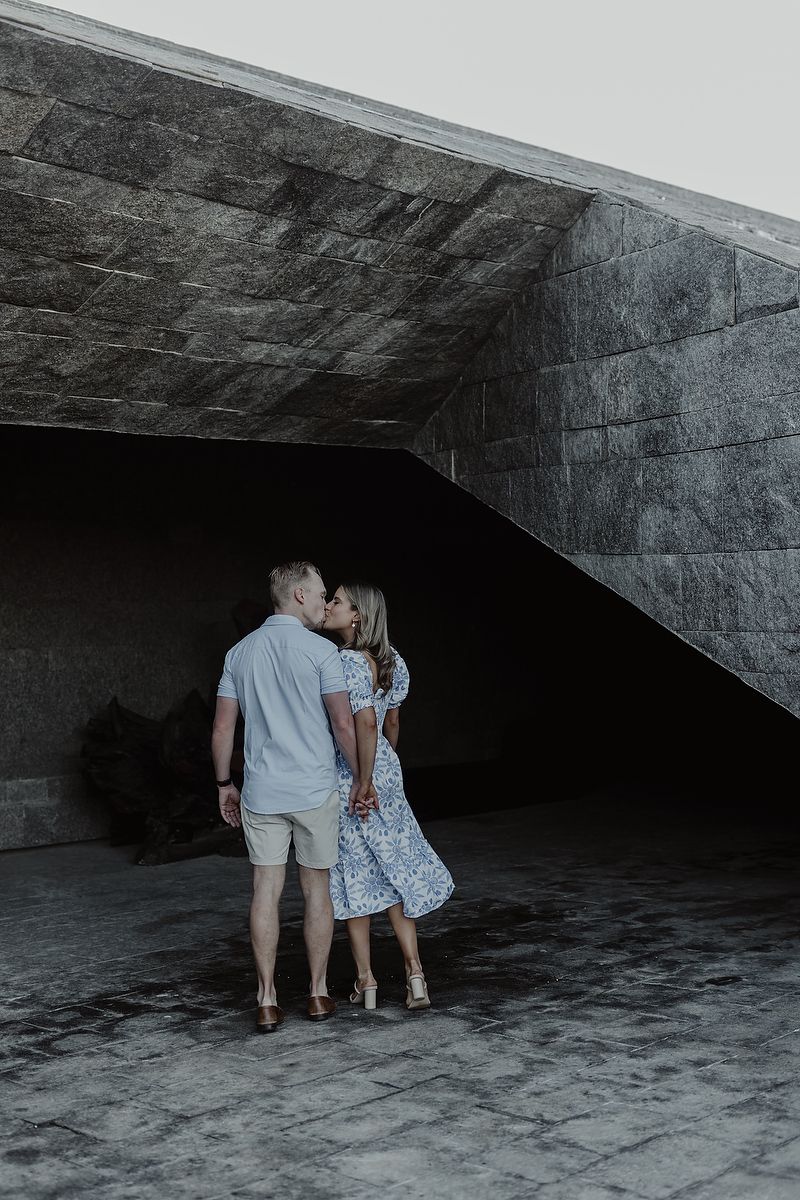 Couple standing together in front of modern stone walls during Playa del Carmen engagement photoshoot.
