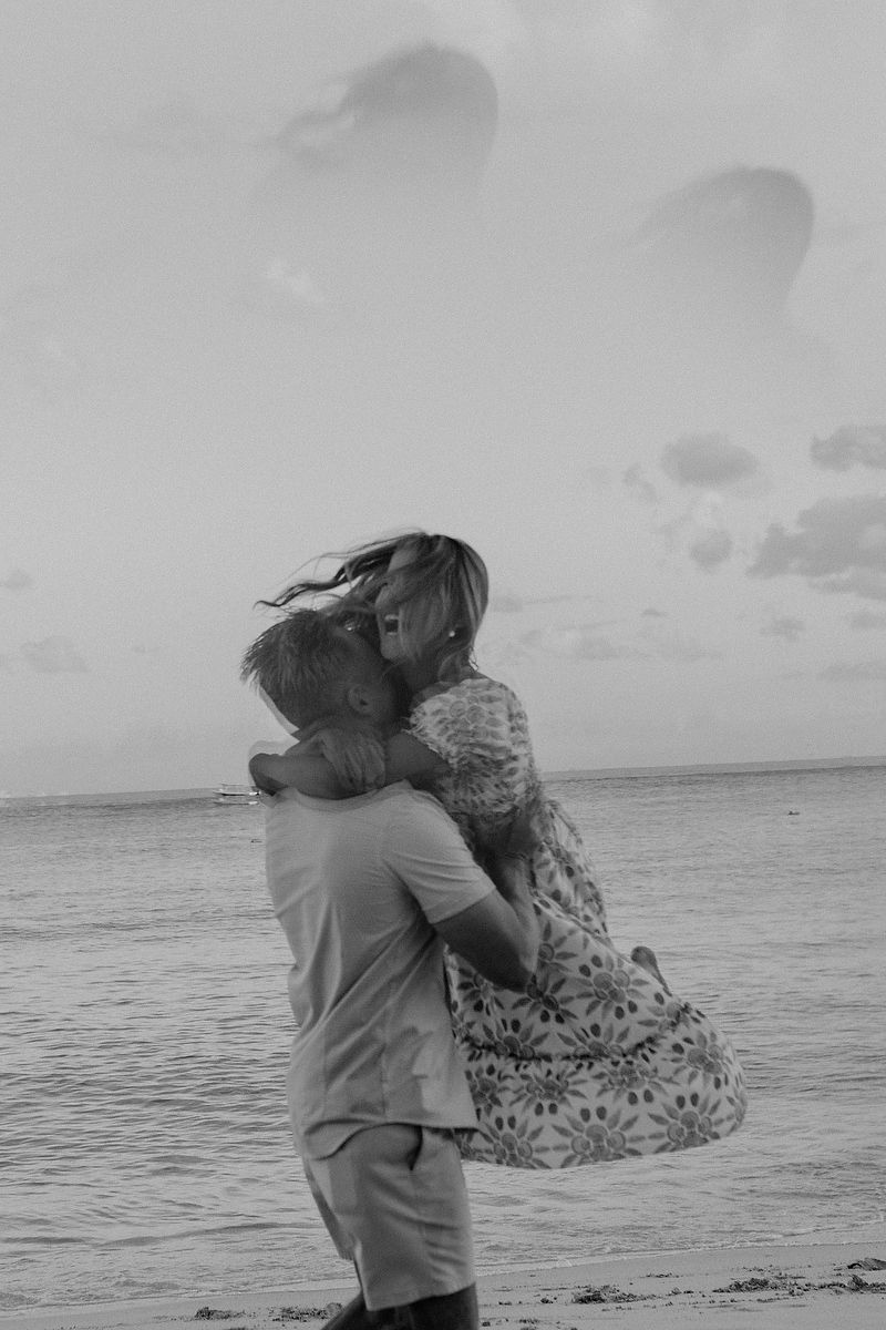 Romantic black and white engagement photo of couple hugging by the Caribbean Sea in Riviera Maya.