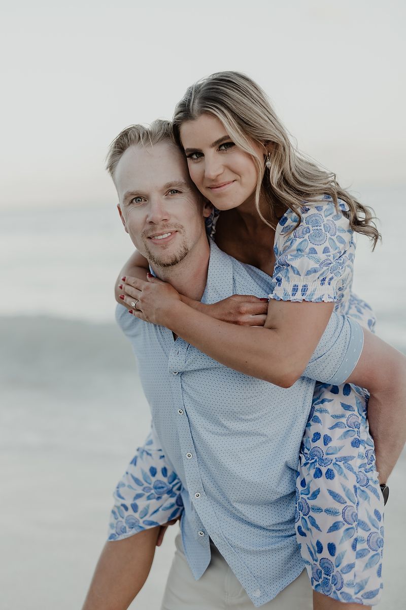 Editorial engagement portrait with playful piggyback pose on the beach in Playa del Carmen.