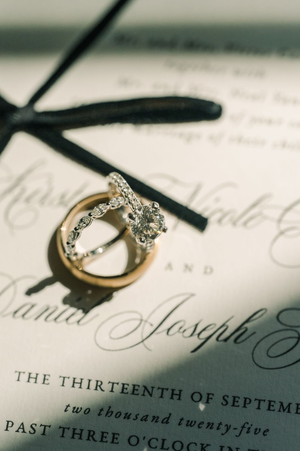 Diamond engagement ring casting shadow on elegant wedding invitation with calligraphy text