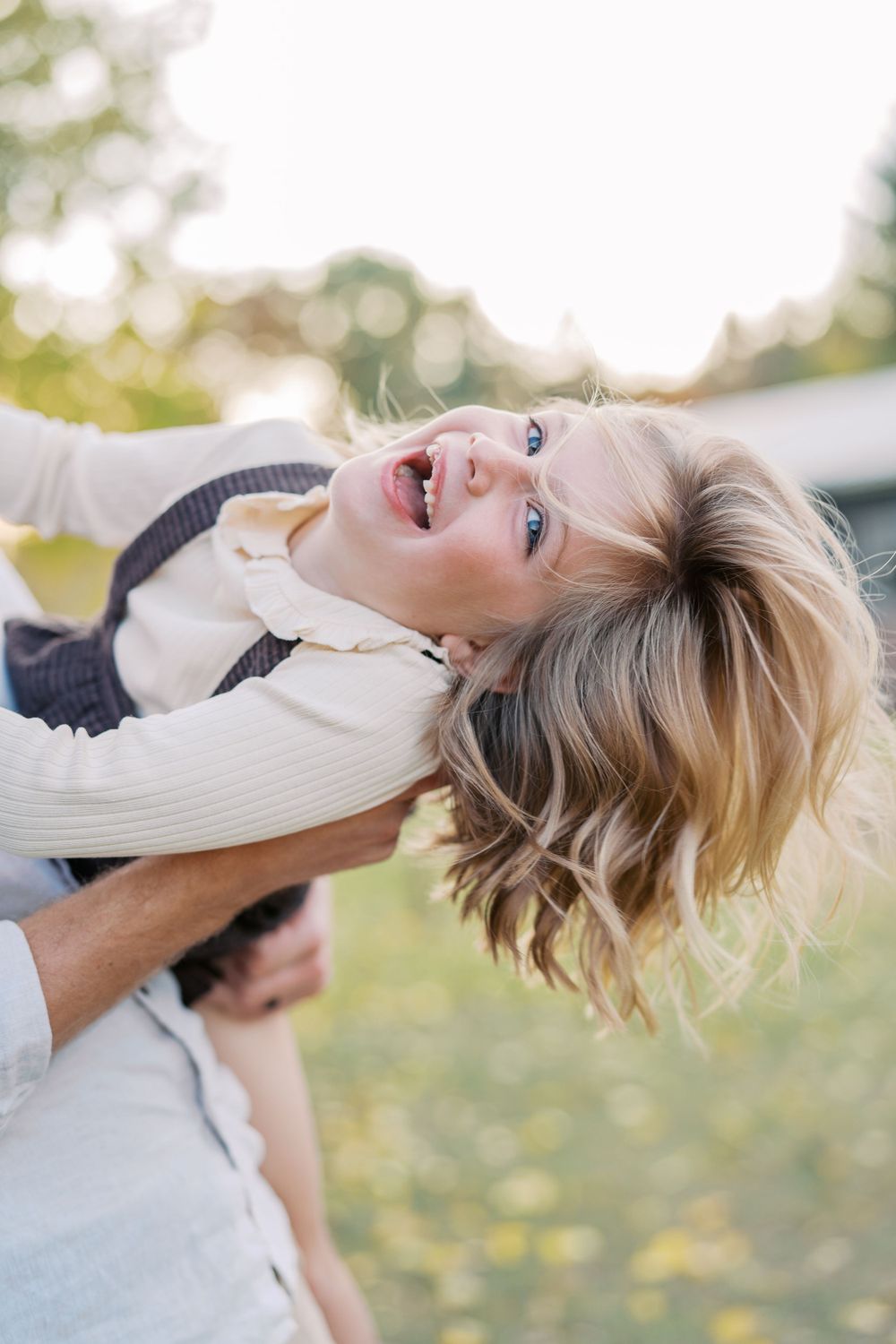 Joyful upside-down portrait with autumn foliage in the background.