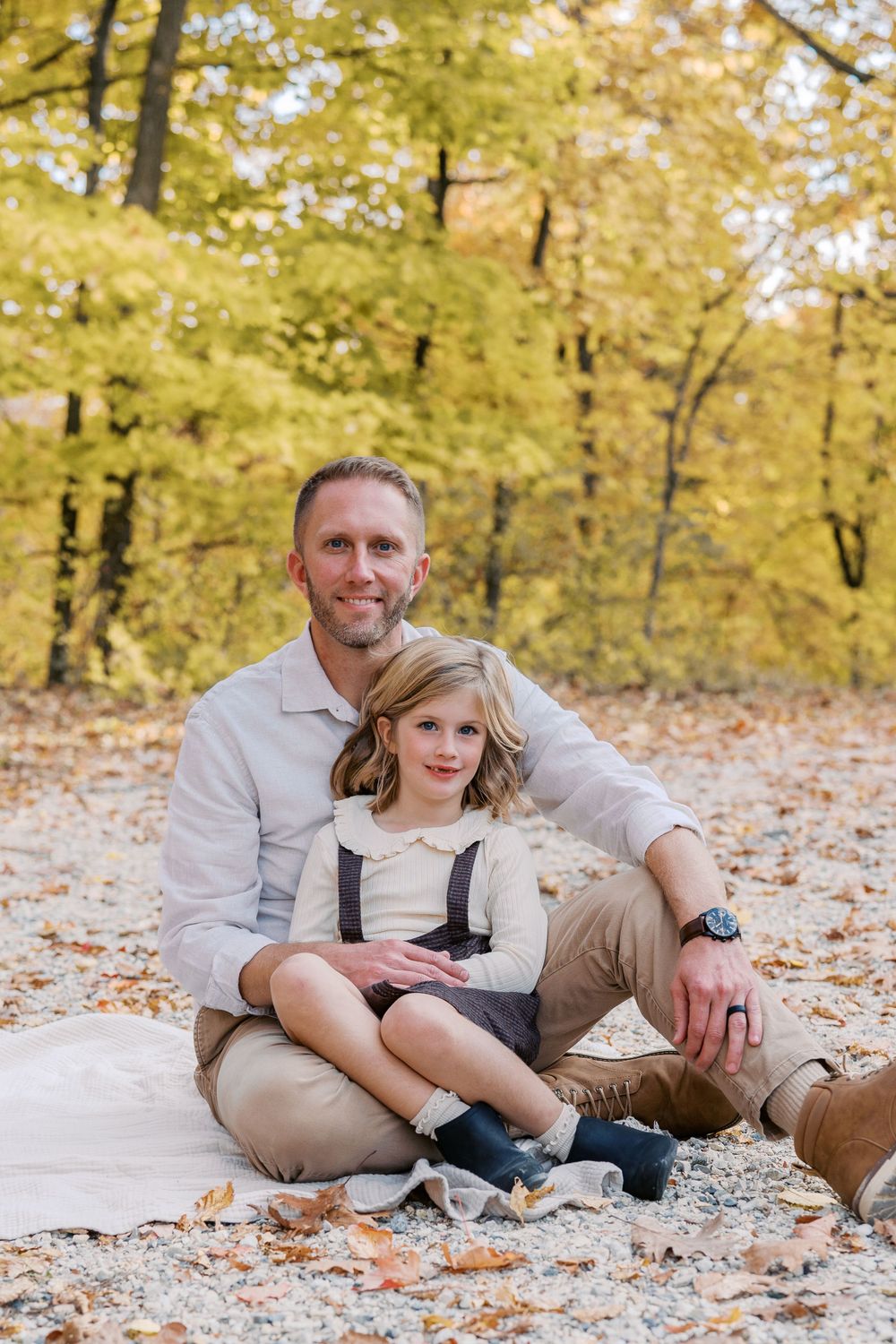 Family members lounging on ground with golden fall foliage in background.