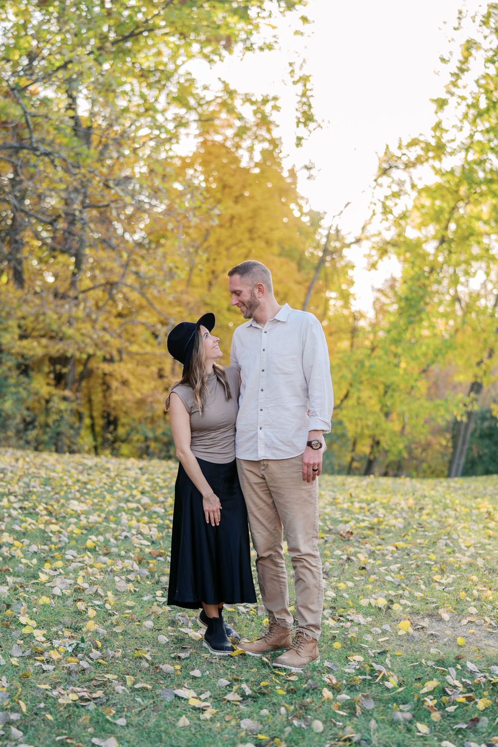 Two people share a tender moment while standing in a field of yellow fall foliage.