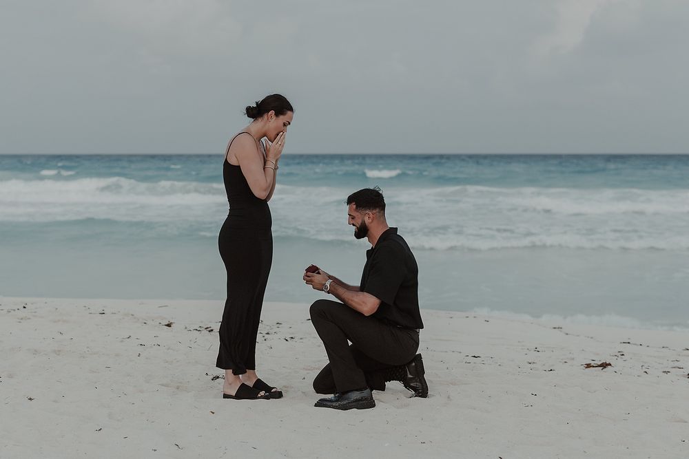 Groom kneeling to propose during an engagement photoshoot at Kempinski Hotel Cancún.
