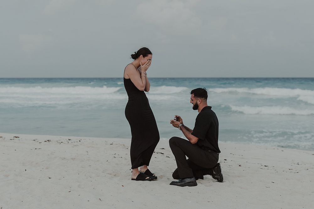 Emotional reaction to the engagement ring during a romantic proposal on Cancún’s beach.