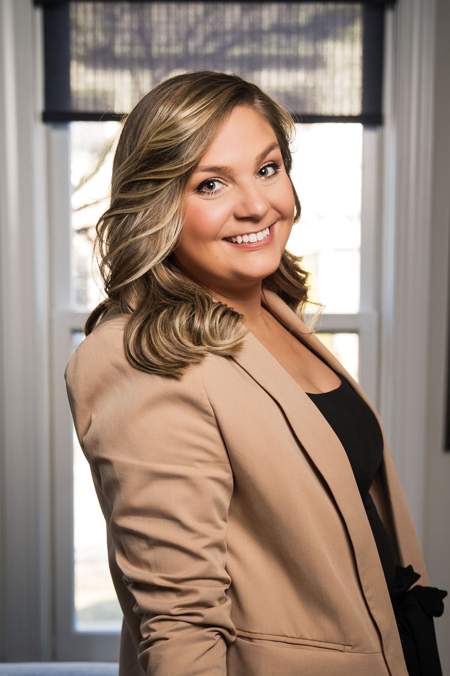 Headshot of a woman leaning on a table with a window behind her taken by Milwaukee headshot and branding photographer Rachel Dickman.