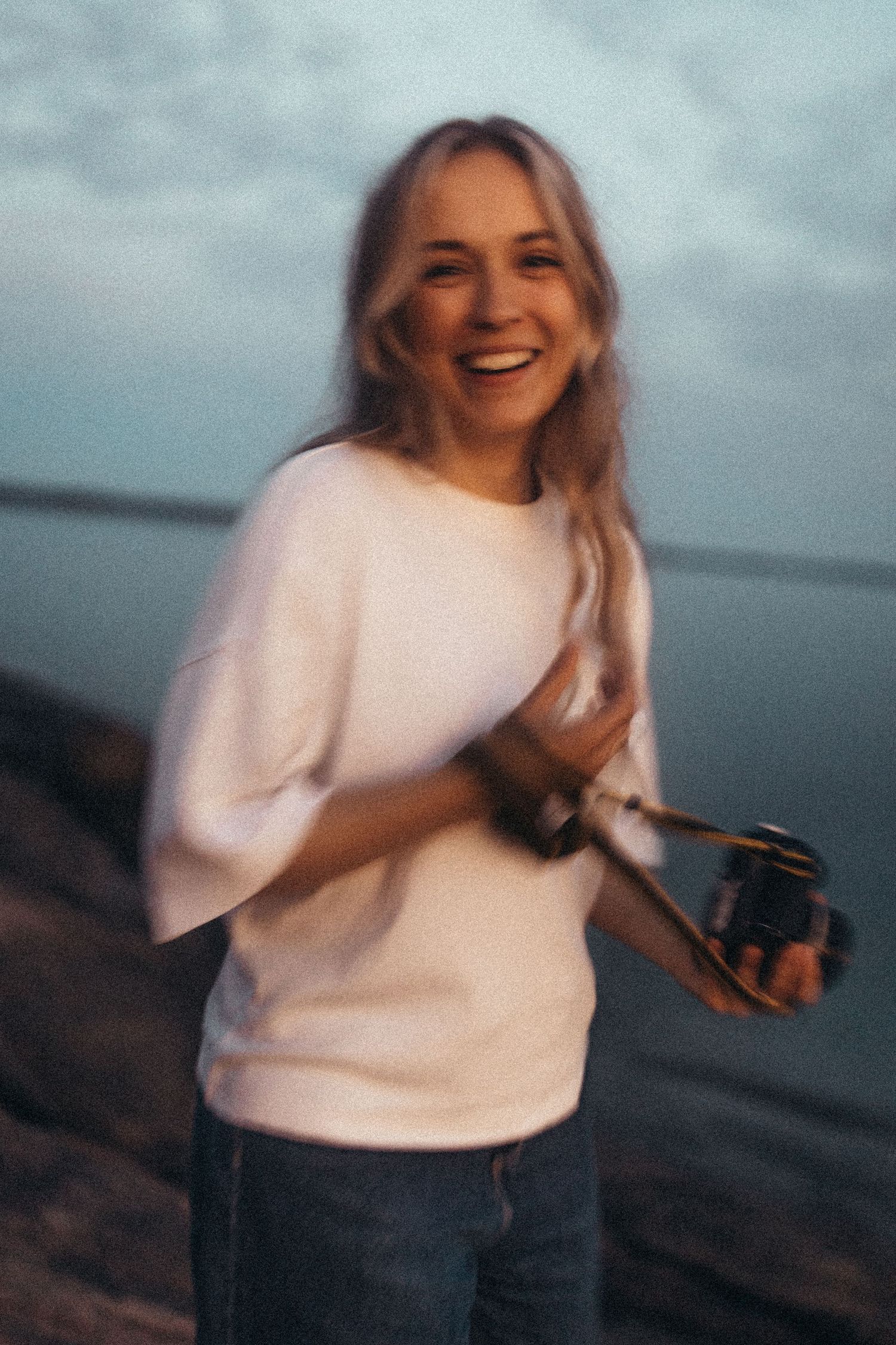 Portrait at sunset with warm golden light and a serene coastal backdrop.
