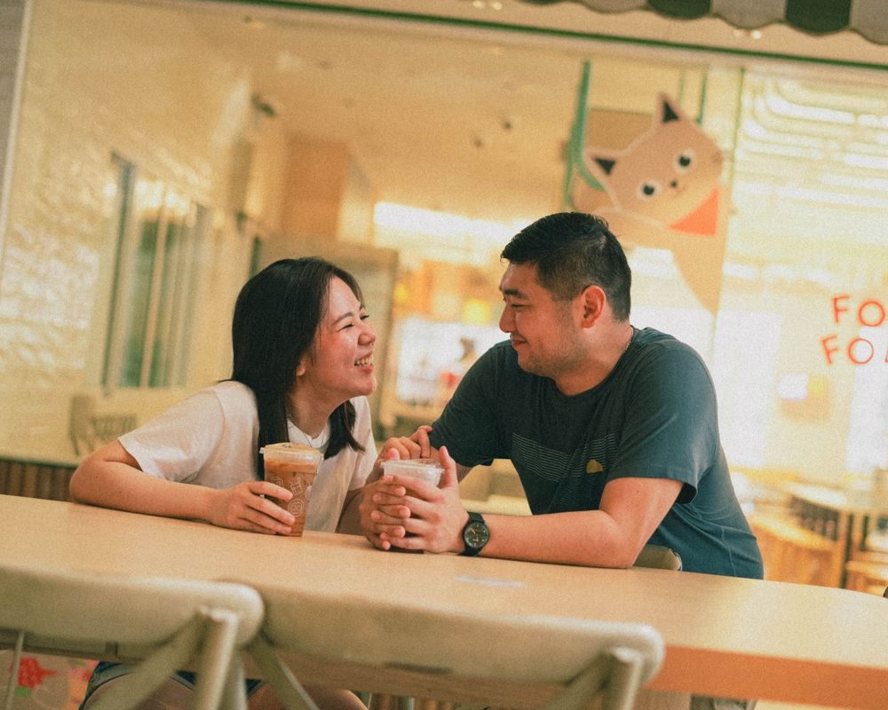 Cozy cafe scene with two people sharing drinks and conversation at a table.