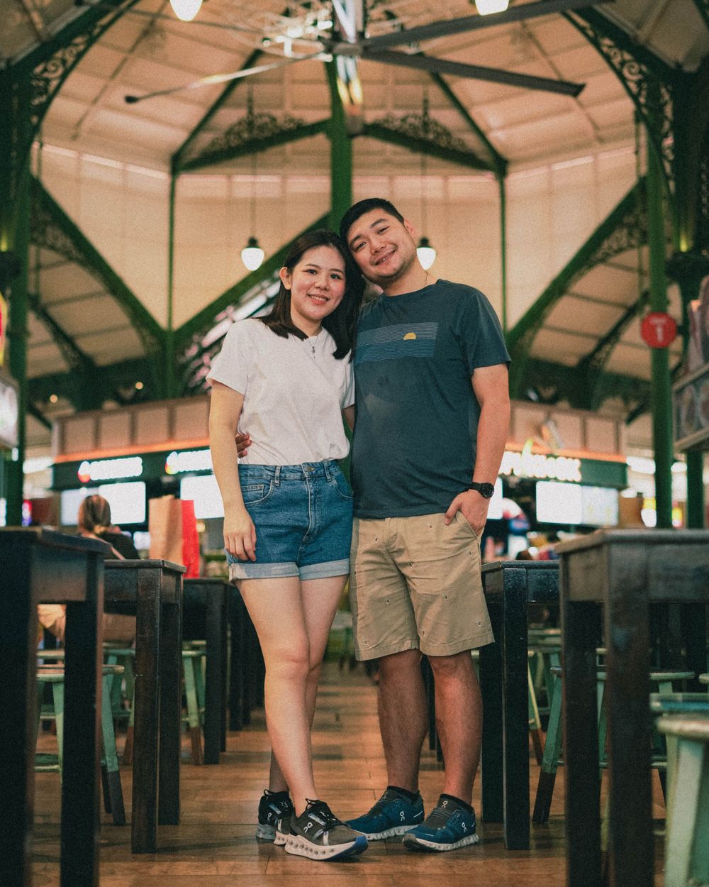 Casual dining scene with two people standing in a restaurant with wooden architectural details.