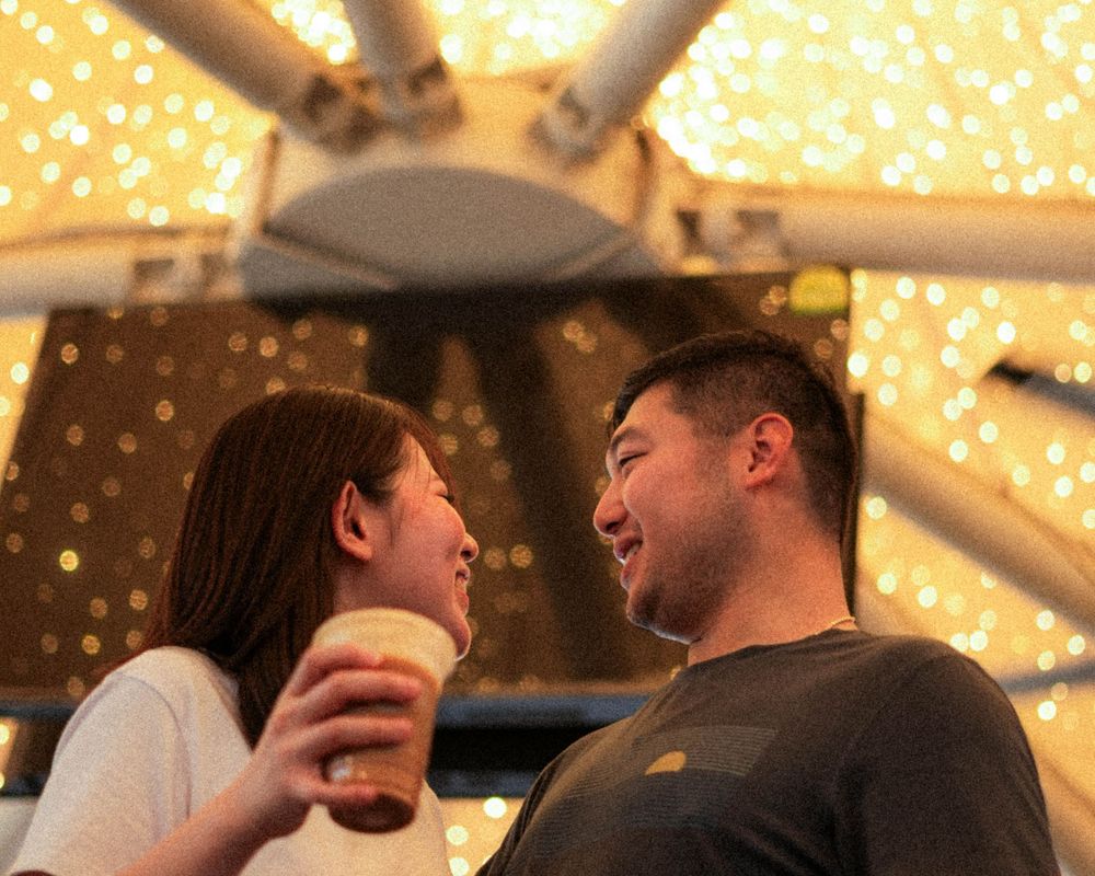 Romantic cafe scene with couple laughing together under warm string lights.