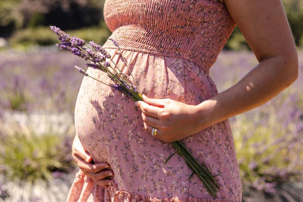 Close-up view of a pink floral maternity dress against a natural outdoor background.