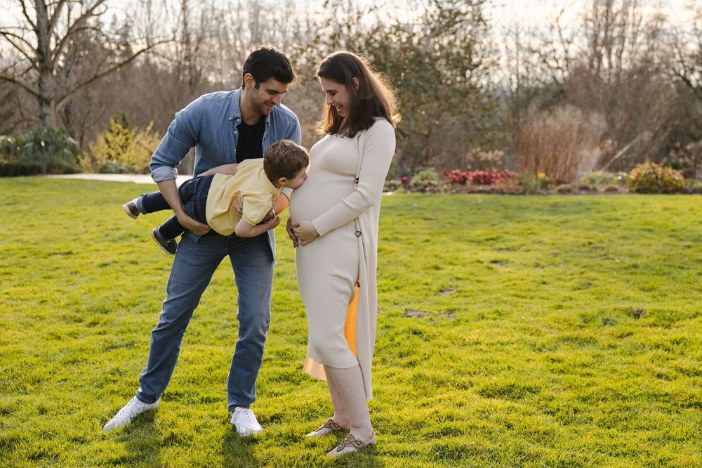 A couple shares a tender moment in a sunny green field while wearing casual spring attire.