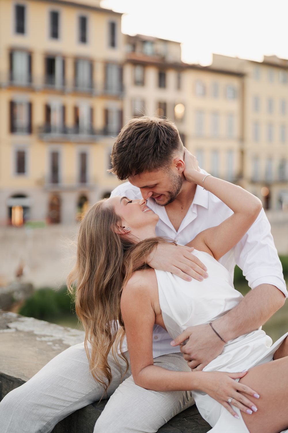 Para narzeczonych podczas romantycznego wschodu słońca w Florencji, patrzą sobie w oczy, siedząc przy rzece Arno, atmosfera pełna magii i mi