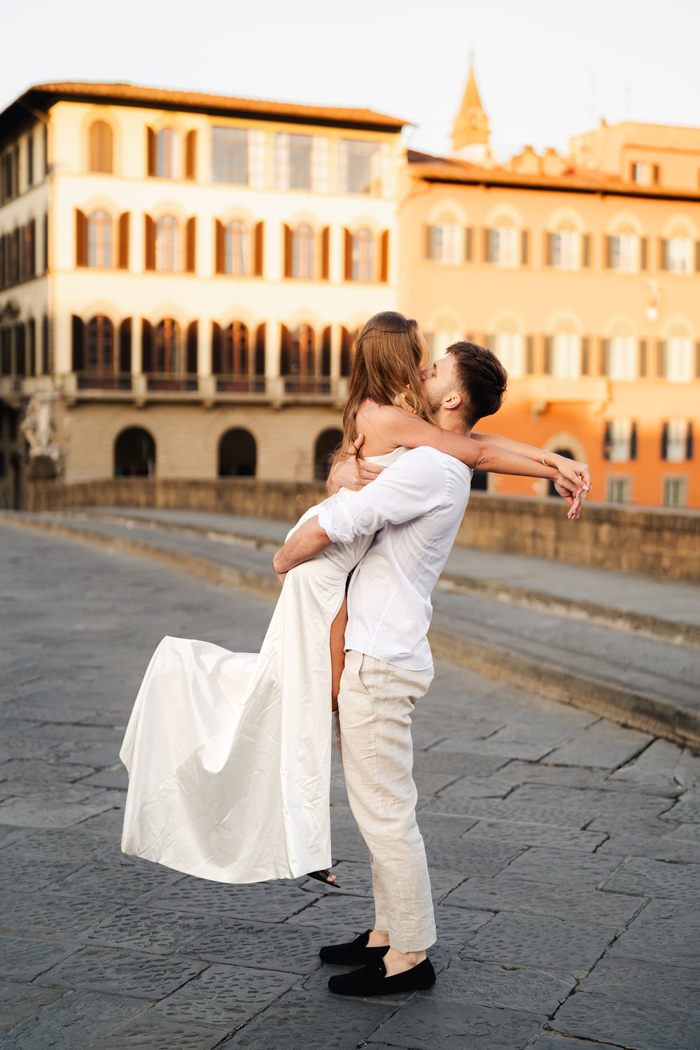 Narzeczeni w objęciach na moście Ponte Vecchio, Florencja, romantyczna sesja narzeczeńska uchwycona w porannym świetle.