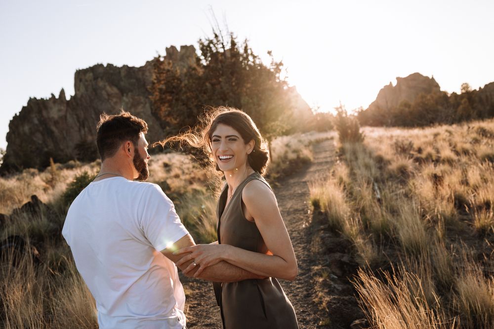 Couple sharing a moment during sunset with desert brush and mountains in background.
