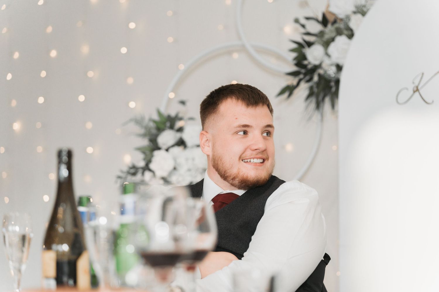 Guest at an elegant wedding reception table with white floral decor and soft string lights in background.