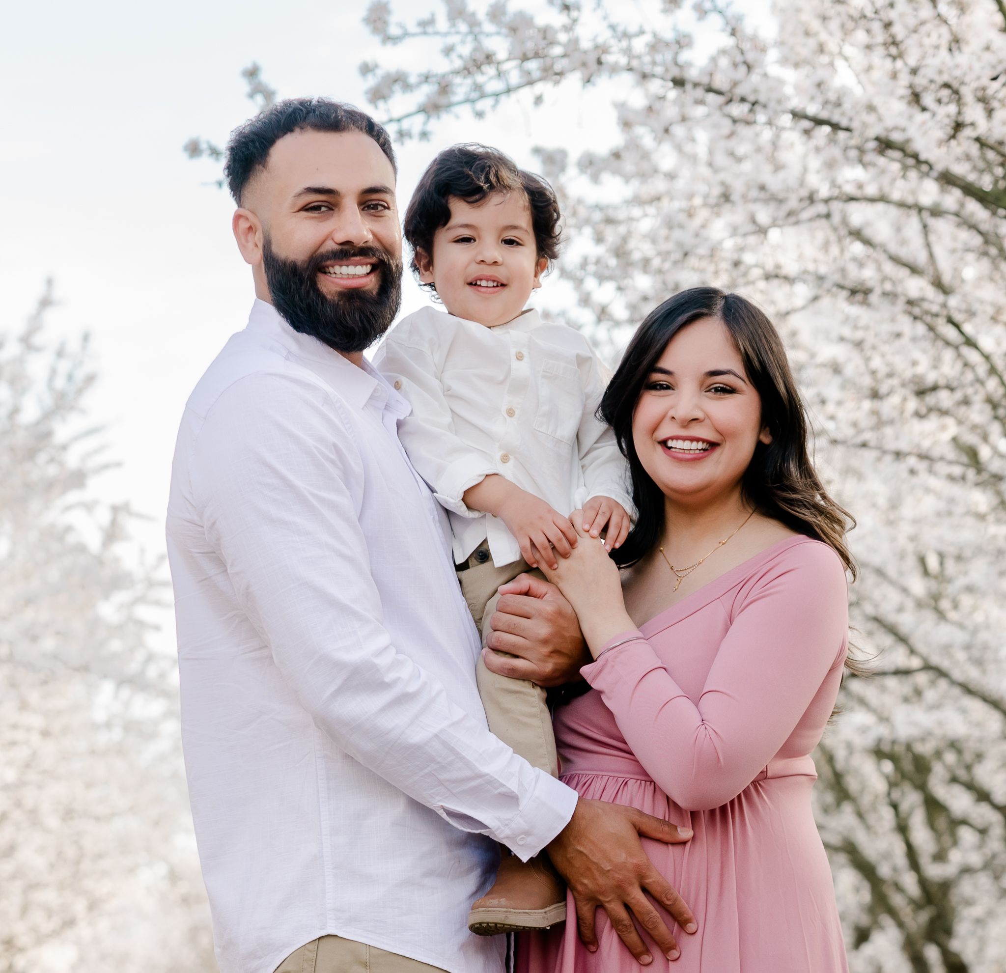 A heartwarming family portrait under blooming cherry trees with coordinated pink and white outfits, Bay Area, CA