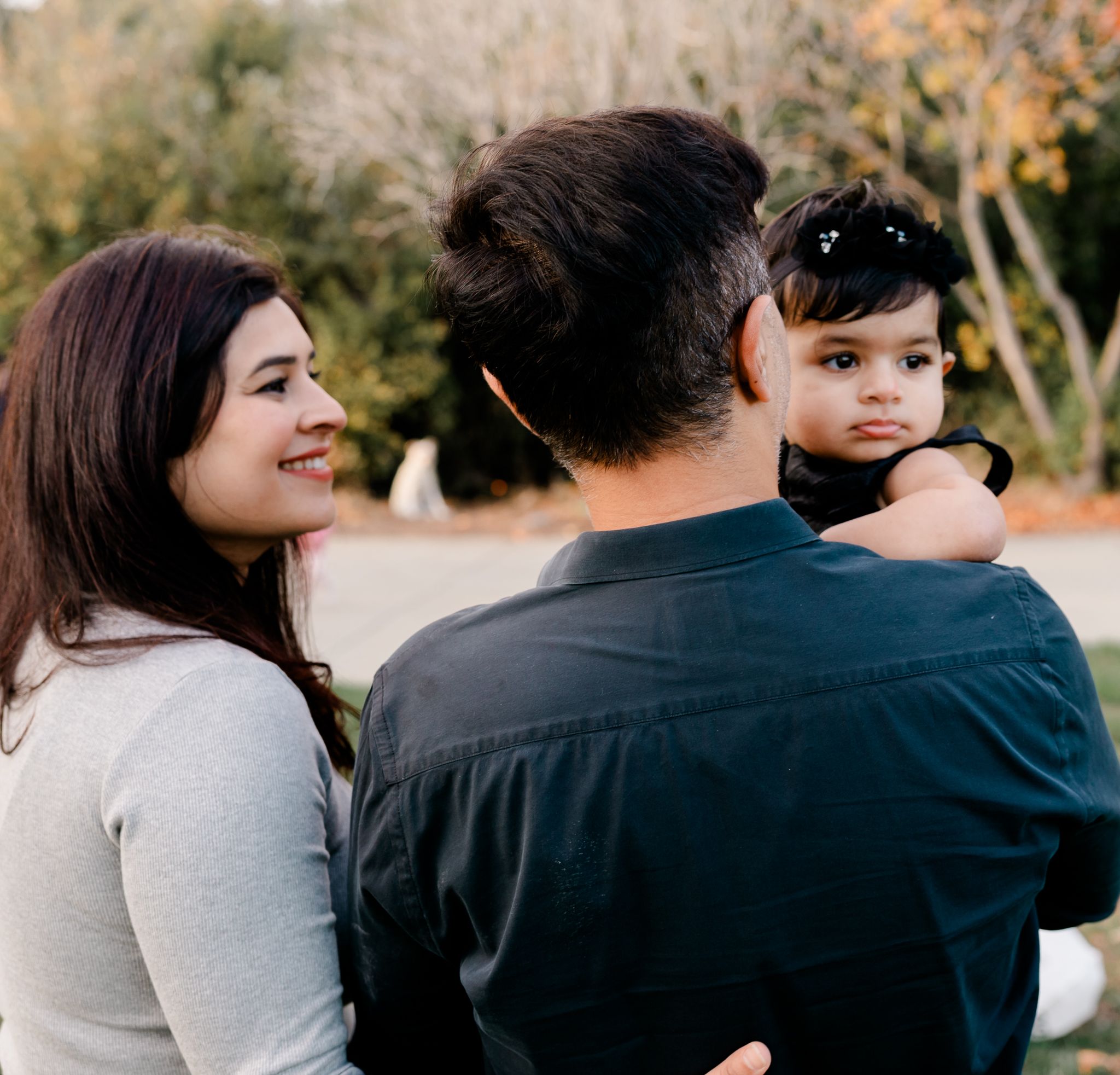 A tender family moment outdoors with natural autumn foliage in the background, San Jose, CA