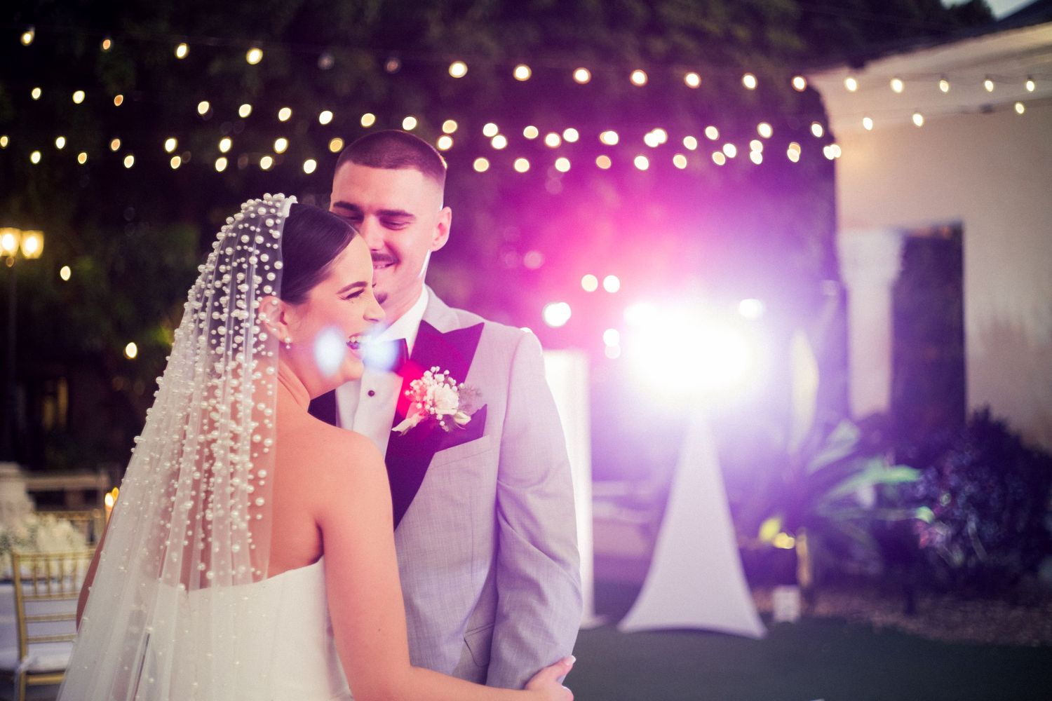 A romantic wedding moment under twinkling lights during an evening reception.
