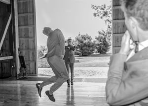 Two people dance together in a barn doorway, captured in nostalgic black and white photography.