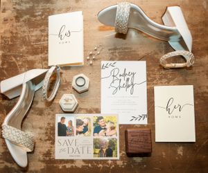 Wedding invitation suite with mint green heels and save the date cards arranged on rustic wooden surface.