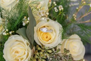 Close-up of cream colored roses with delicate baby's breath and greenery in a wedding bouquet arrangement.