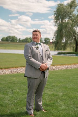 Wedding portrait taken outdoors with green lawn and willow tree in background.