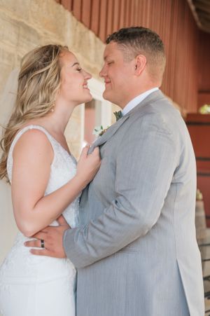 Intimate wedding portrait of couple sharing tender moment against rustic barn wall.