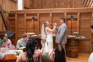 Newlyweds sharing a joyful moment during their rustic barn reception with wooden barrel decor.