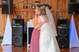 Emotional moment shared during wedding reception inside rustic barn with speaker setup.