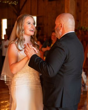 A touching moment during a wedding dance in a rustic barn venue.